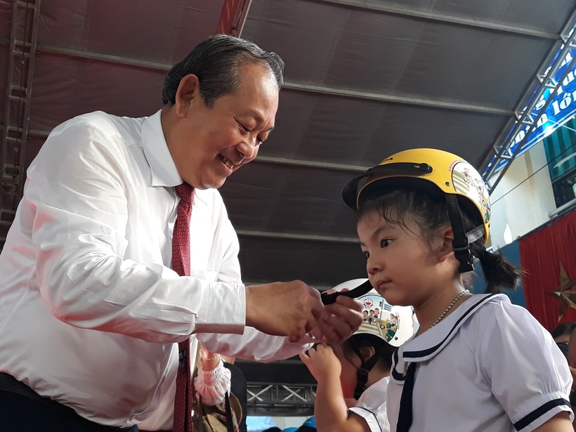  Phó Thủ tướng Trương Hòa Bình hướng dẫn học sinh cách đội mũ bảo hiểm an toàn

