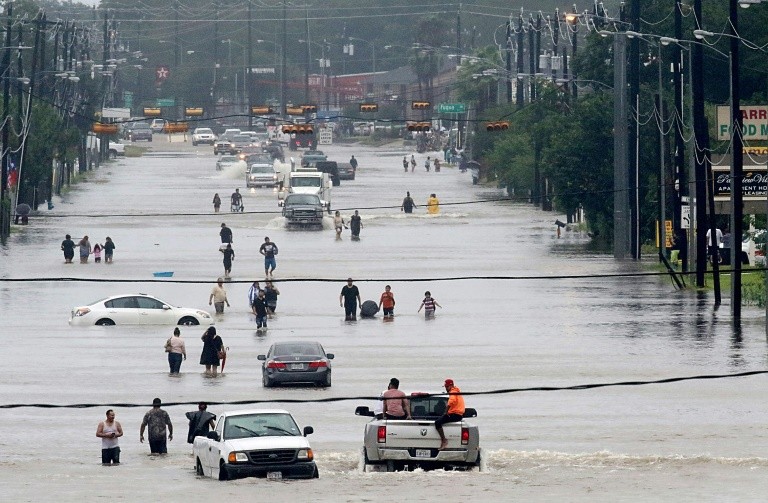 Người dân đi bộ qua đoạn đường bị ngập lụt ở TP Houston vào tháng 8/2017 sau cơn bão nhiệt đới Harvey