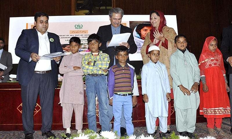 Ông Shafqat Mehmood (đứng giữa, hàng sau) ký vào bản đăng ký học của sáu em nhỏ trong khuôn khổ sự kiện vừa diễn ra