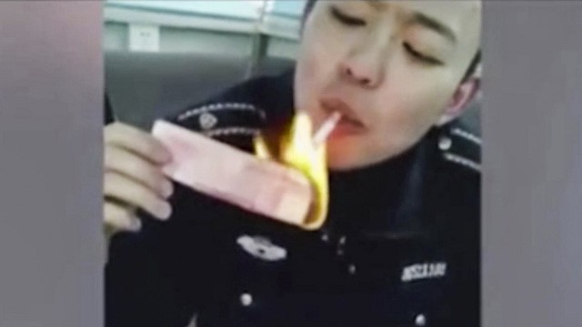 Một trong hai sĩ quan đốt tiền để châm thuốc ở Trung Quốc