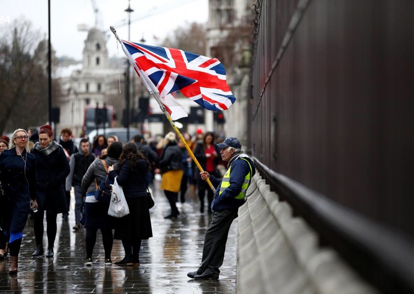 Dòng người thờ ơ đi ngang qua người đàn ông đang thể hiện sự ủng hộ đối với Brexit cũng như bà May, bên ngoài tòa nhà Quốc hội Anh hôm 16/1

