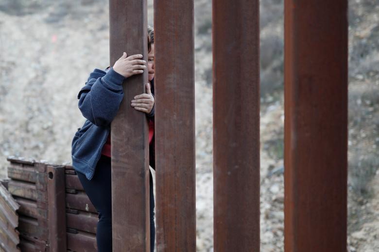 Một phụ nữ nhảy qua bức tường biên giới để vượt biên trái phép từ Mexico sang Mỹ