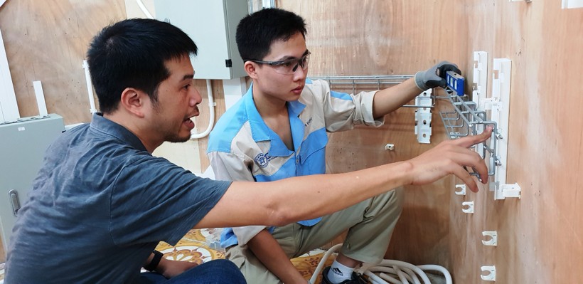 Chuyên gia nghề Lắp đặt điện Nguyễn Quang Huy đang huấn luyện thí sinh Nguyễn Văn Minh