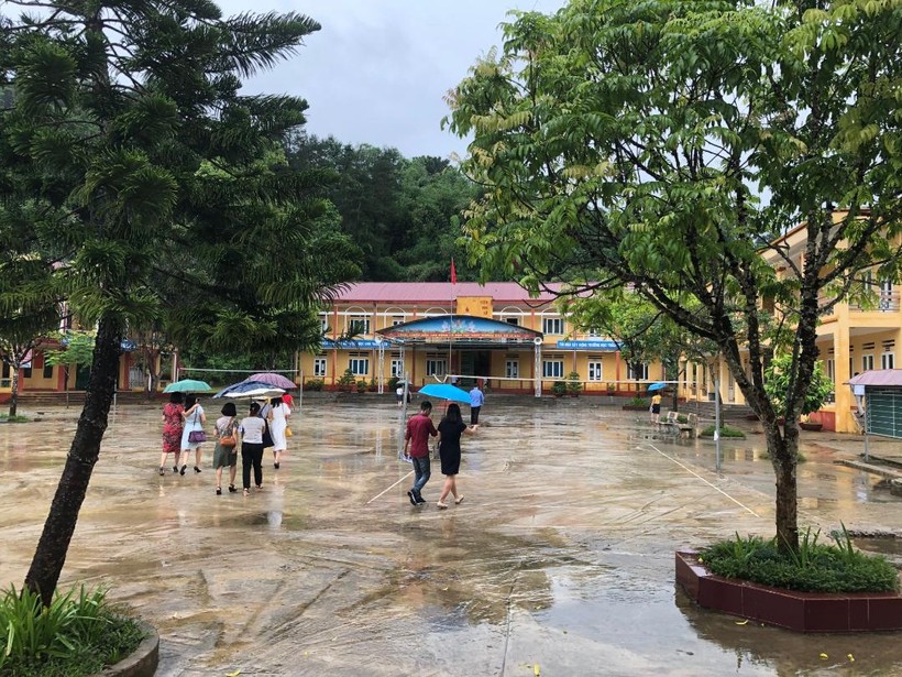 Cán bộ làm thi đến điểm thi THPT Lục Yên trong mưa