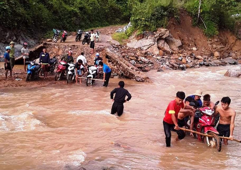 Dân bản khiêng xe qua suối giúp cô giáo Vi Thị Chuyên và Hà Thị Hằng. 	Ảnh: T.g