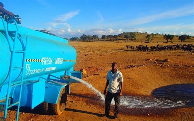 Người nông dân Patrick Kilonzo Mwalua đang chuyền nước từ xe bồn vào một hố bê-tông, trong Công viên quốc gia Tsavo West, Kenya. (Ảnh: This Is Africa).