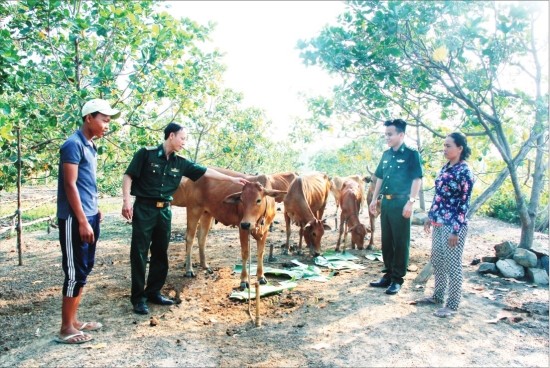 Cán bộ Đồn Biên phòng cửa khẩu Lộc Thịnh thăm gia đình được đơn vị tặng bò giống. Ảnh: Văn Hoàn