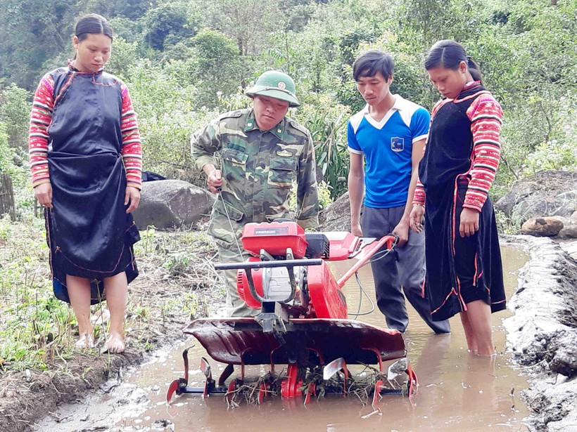 Bộ đội biên phòng hướng dẫn người dân sử dụng máy cày làm đất trồng lúa nước.