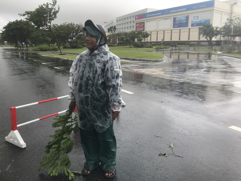 Ông Trương Thọ mặc chiếc áo mưa mỏng đứng giữa đường để chỉ cho người dân đi lại vì phía trước bị nước ngập sâu.