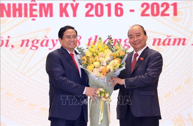 Chủ tịch nước Nguyễn Xuân Phúc, nguyên Thủ tướng Chính phủ tặng hoa chúc mừng Thủ tướng Chính phủ Phạm Minh Chính. Ảnh: TTXVN