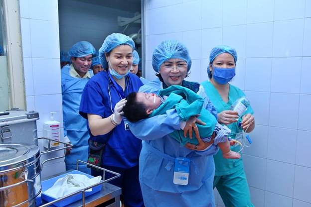 Phó Chủ tịch nước Đặng Thị Ngọc Thình bế bệnh nhi vào phòng phẫu thuật nụ cười.