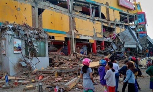 Người dân ở Palu đứng trước một ngôi nhà bị đổ sập sau trận động đất. Ảnh:Reuters.