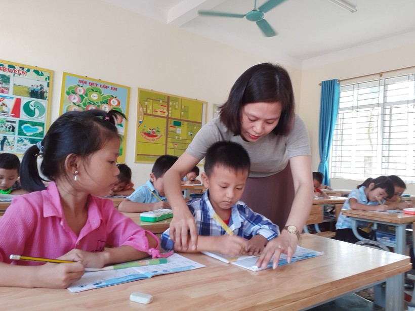 Cô Hồ Thị Trang (GV lớp 1A) trường Tiểu học Hồ Tông Mục, Can Lộc đang hướng dẫn học sinh viết chữ. (Ảnh: Lê Văn Vỵ)
